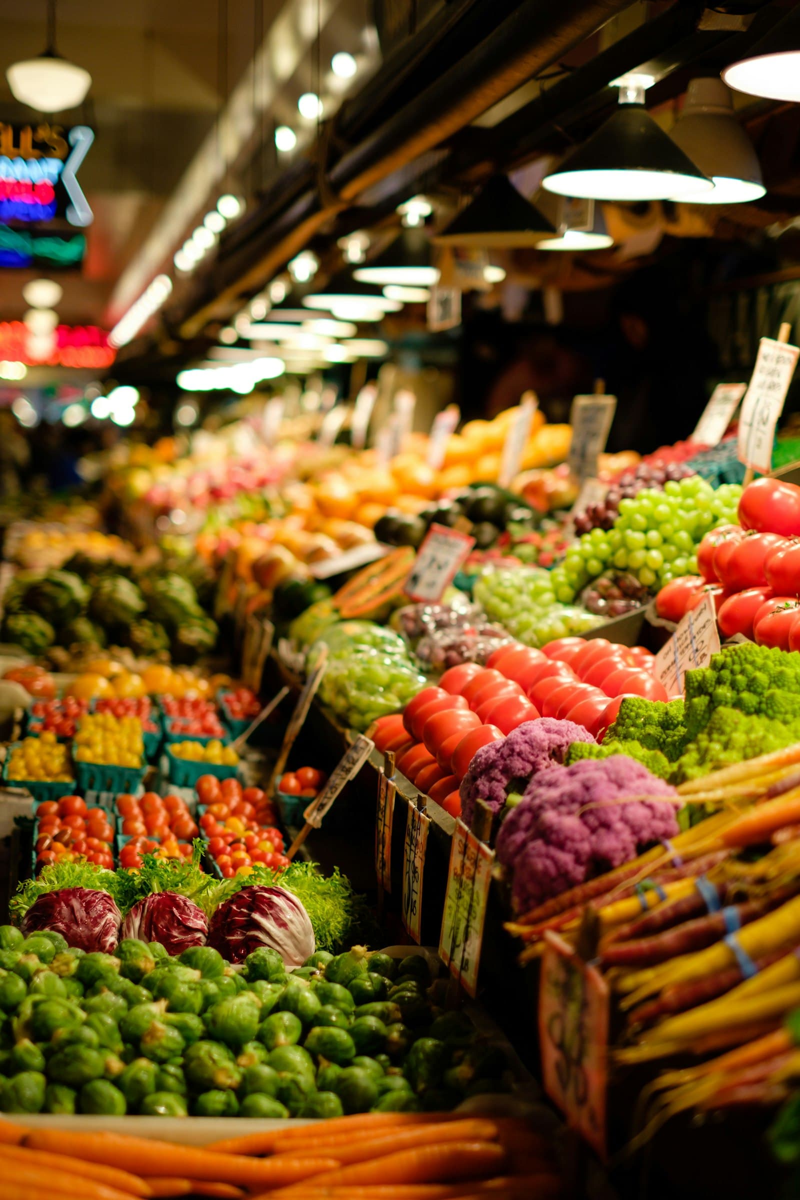 Auslage eines Marktstands mit Rosenkohl, Radicchio, Tomaten, Romanesco und Bundmöhren